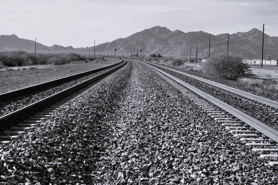 Black and white landscape featuring two railroad tracks.